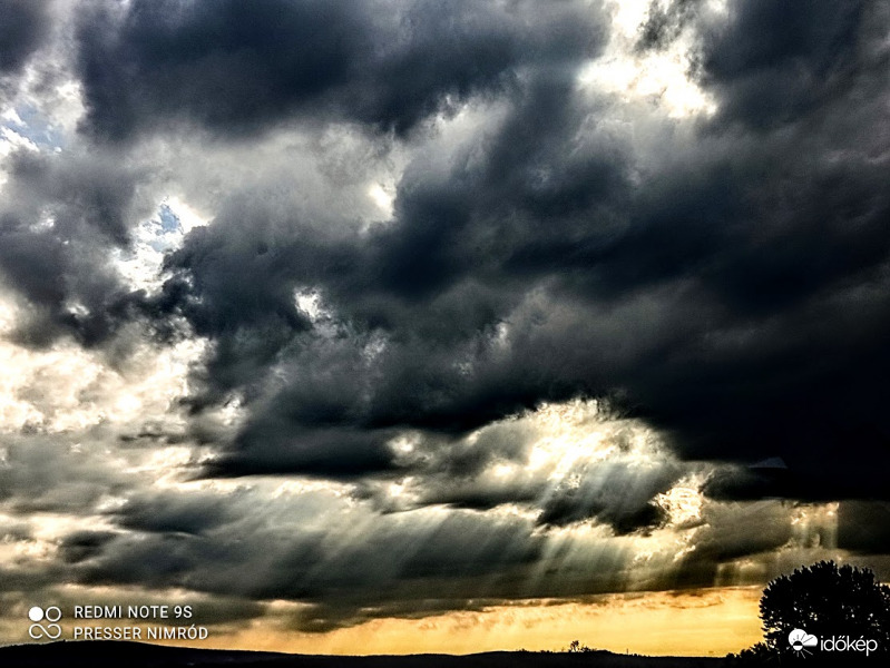 A lemenő nap fénye, ahogy a felhők mögül átszűrődik