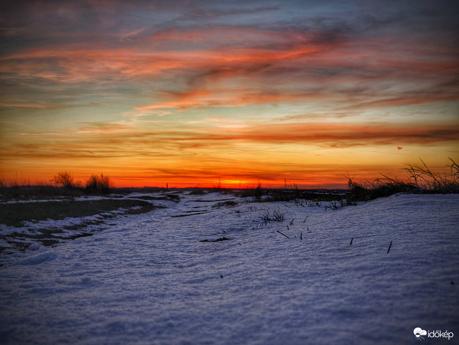 Hideg, havas táj és a forrósodó alkonyati égbolt