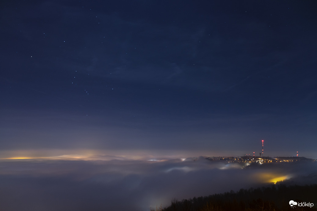 Budapestet beborító ködtenger az ébredő Orion csillagképpel. Háttérben a Széchenyi-hegy látható. 