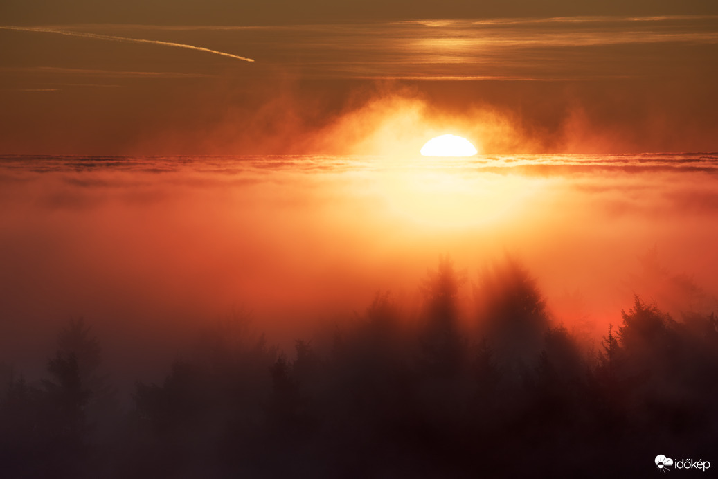 Színpompás, tüzes naplemente a ködtenger határán