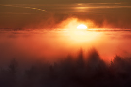 Színpompás, tüzes naplemente a ködtenger határán