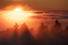 Színpompás, tüzes naplemente a ködtenger határán